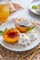 A plate of two peach halves with ice cream and nuts on top