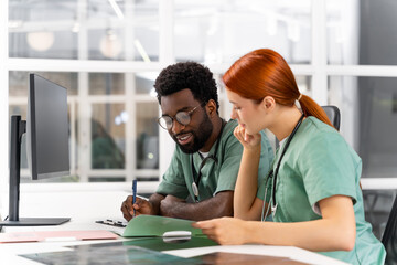 Doctor and nurse discuss treatment plan for patient sitting at table in clinic