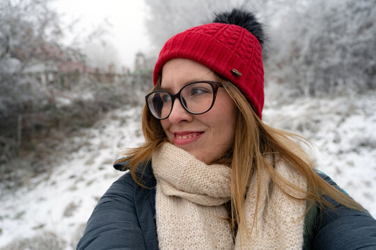 young woman in winter, snowy background, red winter hat
