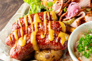 A delicious plate featuring grilled sausages topped with mustard, served with fresh greens, pickles, and a variety of meats. Ideal for food enthusiasts and culinary presentations.