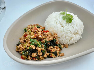  Pad Krapao Gai, a popular Thai dish made with stir-fried chicken, holy basil leaves, and chili peppers, served over rice.