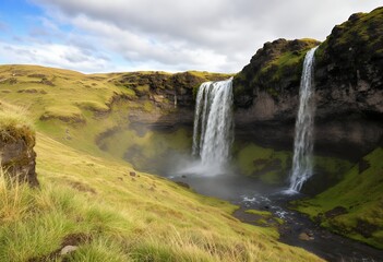 Obraz premium Icelandic Waterfalls: A Serene Landscape of Cascading Water and Mossy Green Hills