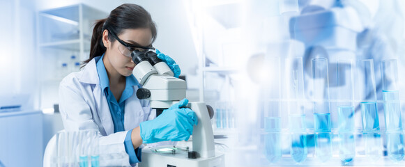 Asian Researcher using a microscope in the clinical lab.Female Researcher working in the clinical...