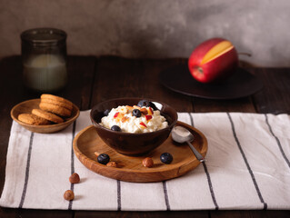 Fresh Cottage cheese with blueberries and sliced ​​apple in a brown bowl on a dark wooden background. Breakfast concept.