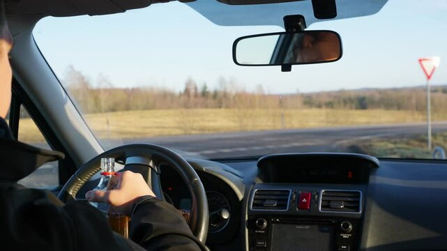 Driver takes a drink from bottle while driving, interior car perspective, dangerous reckless behaviour
