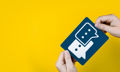 Hand holding a paper conversation speech bubble on yellow background. with copy space.  Concept of...