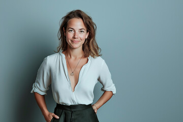 Half-length portrait of a woman in her 30s with long hair and a white shirt on a gray background