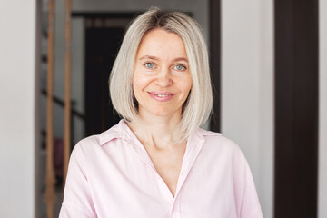 Smiling middle aged mature woman looking at camera at home