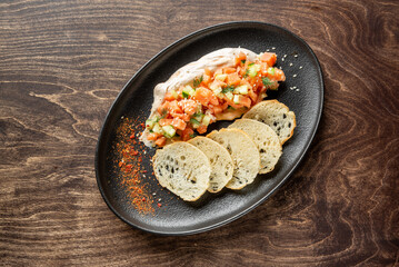 A stylish platter featuring a creamy spread topped with fresh diced salmon and cucumbers, garnished with dill, accompanied by slices of artisan bread. Perfect for appetizers or gourmet dining.