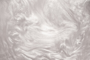 Fototapeta premium Shimmering silver abstract background. Liquid glitter paint texture waves and swirls. Beautiful shiny white glitter texture. Metallic silver paint close-up as a holiday background.