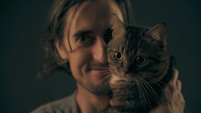 Young Man with Cat of an attractive male holding a cat showcasing his big eyes and long hair in a warm intimate moment