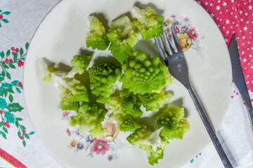 Boiled Romanesco broccoli pieces on dish on table with tablecloth