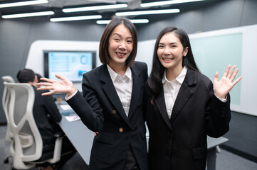 Two businesswomen standing in a group meeting around a table in a modern office. There are documents, laptops. Everyone is brainstorming, planning sales, digital marketing and growth strategies.