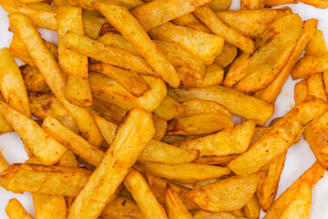 Heap of French fries on dish, top view close-up