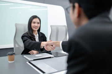 business people, men and women meeting around a table in a modern office with documents, laptops and handshakes. Everyone brainstorming, planning sales, digital marketing and growth strategies.
