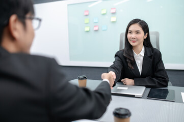 business people, men and women meeting around a table in a modern office with documents, laptops and handshakes. Everyone brainstorming, planning sales, digital marketing and growth strategies.