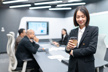 Beautiful young businesswoman meeting in modern office with documents, laptop and coffee to keep her awake. Everyone brainstorming, planning sales, digital marketing and growth strategies.