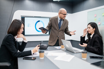 Male software developer meeting in modern office with stressed employees, documents, laptops, sales planning, digital marketing and growth strategies, analysis with colorful charts and graphs.