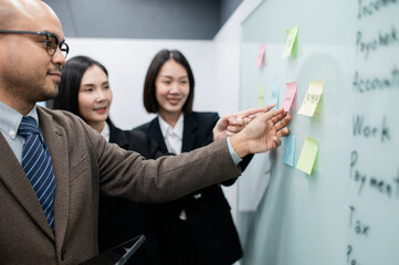 Businessman, woman, smiling, holding laptop, post-it notes, sales planning, digital marketing, growth strategy, marketing goals, analysis with colorful charts and graphs.
