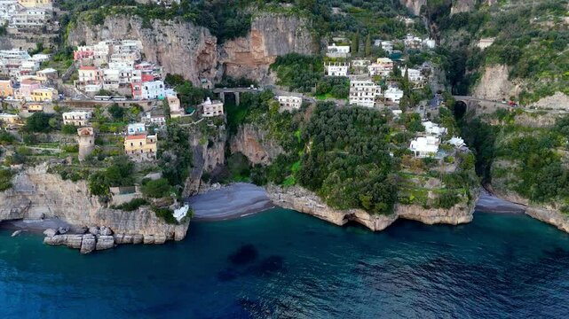 Aerial footage of Amalfi old traditional south Italy village laid on the coastline of Salerno , drone reveals scenic seascape in conca deli marini beach at sunset