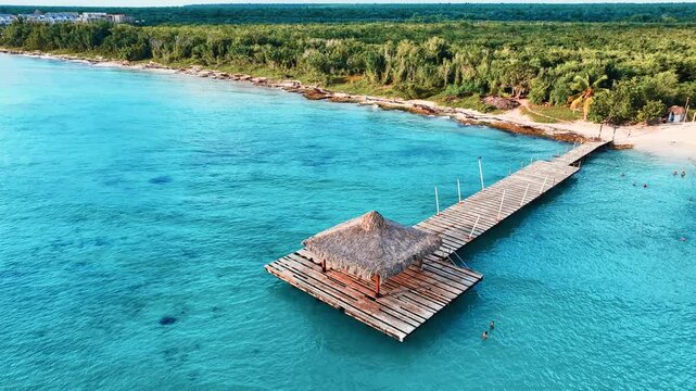 Seascape with a pier going into the ocean. Summer, travel, vacation and relaxation concept. Romantic wooden pier. Calm turquoise Caribbean Sea, Dominican Republic surf. Summer beach holiday.