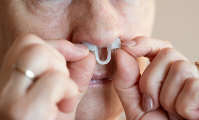 Portrait of aged woman wearing nose anti-snoring device.