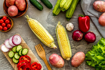 Autumn harvest. Vegetables - potato,cucumber, corn, greenery - on light stone background top-down