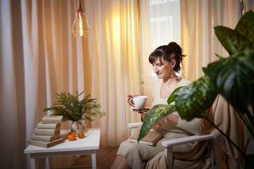 Middle-aged woman enjoying a relaxing evening in a cozy apartment with a cup of tea