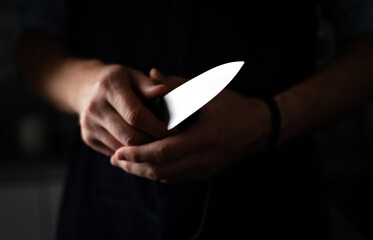 Man Holds Sharp Kitchen Knife in black room