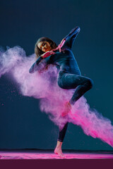 Dynamic female dancer in motion, surrounded by vibrant pink powder explosion, expressing energy, grace, and artistic movement in a dramatic setting.