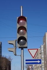 Red traffic light with road signs on a sunny day in the city