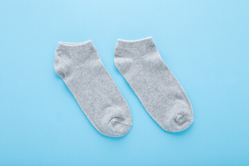 Pair of new light gray short socks on blue table background. Pastel color. Closeup. Top down view.