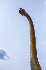 Tall dinosaur sculpture set against a blue sky