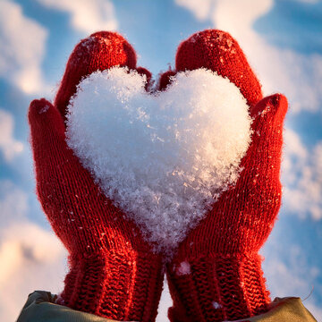 Neve a forma di cuore tenuti in mano da una ragazza con guanti di lana rossa