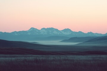 Obraz premium A photograph of the silhouette of mountains in the distance, with a light pink sky and a distant mountain range with snow on top.