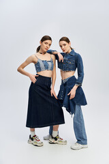 Beautiful twin sisters showcasing unique denim styles in a modern setting