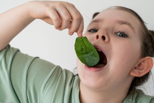 Little girl eating spinach. Concept of healthy food and vitamins. Selected focus. Close-up.