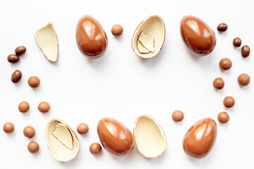 Broken and whole chocolate egg on white background, top view. Chocolate background
