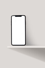 A smartphone with a blank white screen is placed on a minimalist shelf, perfect for use as a mockup model