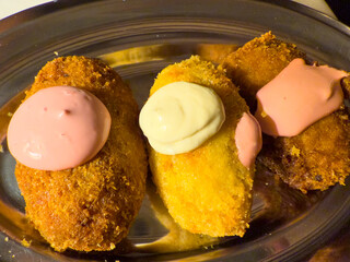 Deep fried pastry filled with colors and flavors on metal tray