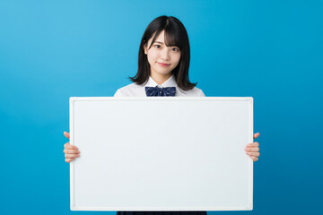 Fototapeta premium ホワイトボードを持つ女性学生、目標、メッセージ