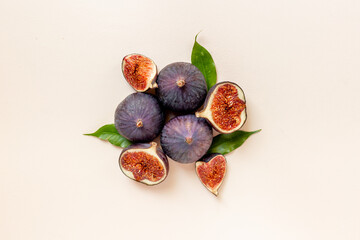 Whole and cut fresh figs with green leaves on stone table. Top view