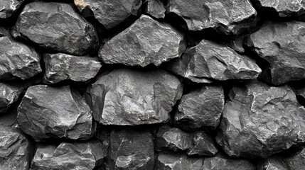 Fototapeta premium A close-up view of a rugged stone wall made of dark, textured rocks, showcasing natural patterns and colors