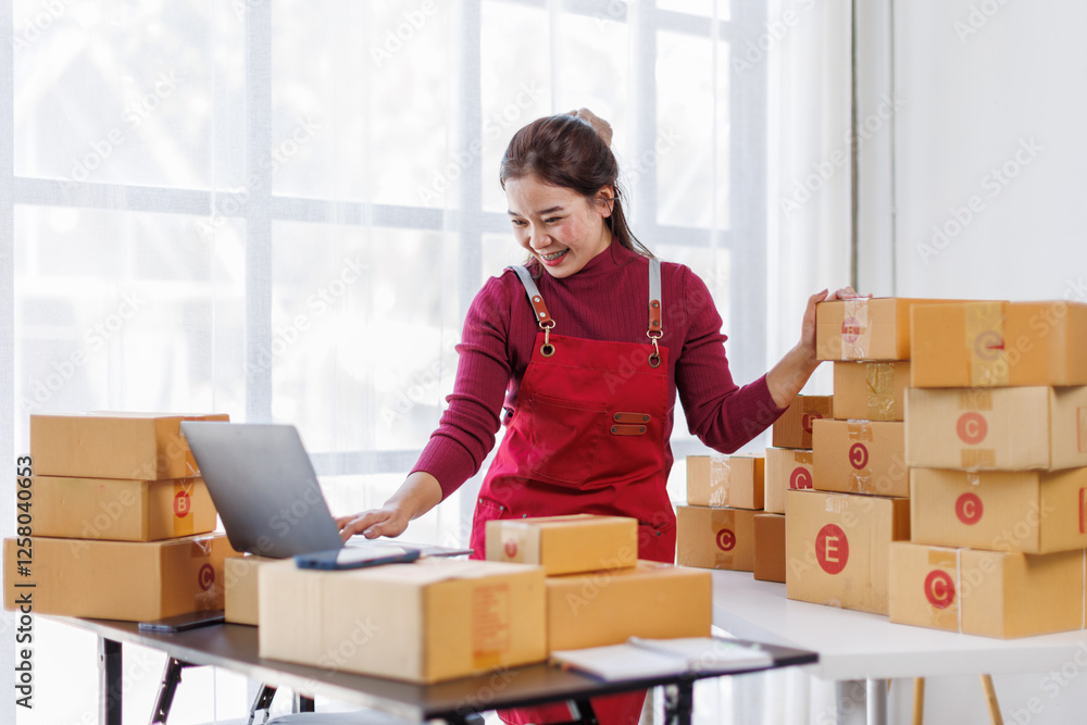 Wall mural Portrait of Asian young woman SME working with a box at workplace. start-up small business owner, small business entrepreneur SME or freelance business online and delivery concept.
