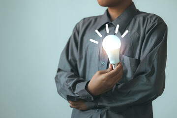 Person holding a glowing light bulb with moving lines around it, symbolizing ideas and innovation.