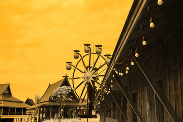 Infrared photography, a ferris wheel set against a backdrop of buildings, all under a sky that has...