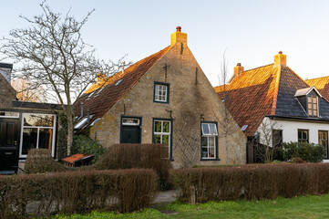A charming historic house with a thatched roof and brick walls in the village of Schiermonnikoog, bathed in warm evening light