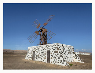 Artistic photo of windmill in bright sunrise light. Las Lajas, Fuertvenetura, Spain