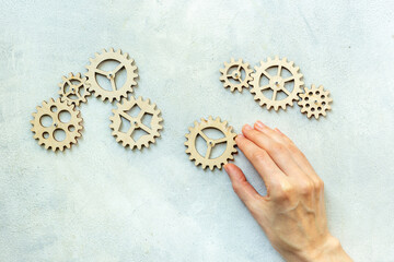 Hand is adding a gear to a chain of cogwheels. Concept of teamwork and togetherness
