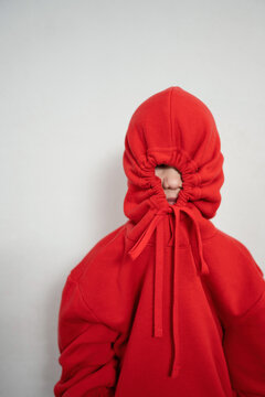 Child in red hoodie with face hidden behind drawstrings
